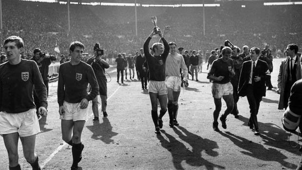 England captain Bobby Moore (1941 - 1993) holds up the Jules Rimet trophy after his team's victory over West Germany in the final of the World Cup Final at Wembley Stadium, London. Goalkeeper Gordon Banks is on the right with Geoff Hurst on the left.   (Photo by Central Press/Getty Images)